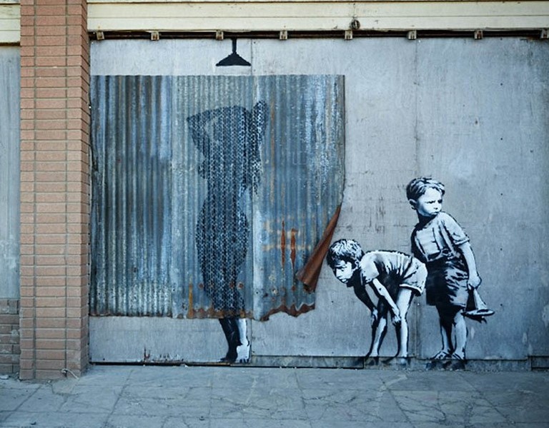 A humorous mural depicting two children peeking at a woman in the shower. Painted at Dismaland (2015).Photo: banksy.co.uk