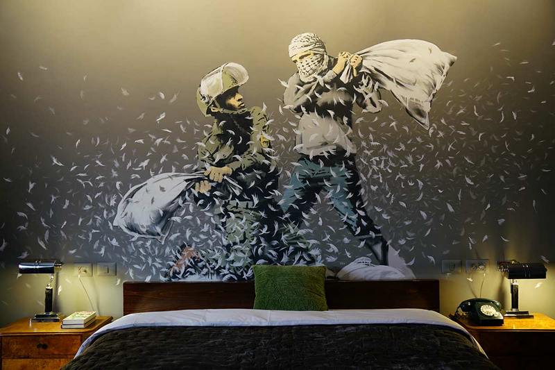 A room at the Walled Off Hotel in Bethlehem. Above the bed is a mural depicting a pillow fight between an Israeli soldier and a Palestinian.Photo: banksy.co.uk