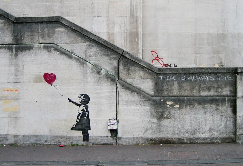 The iconic “Girl with Balloon” mural, painted on a wall in the West Bank (2002). A framed version of this image was famously shredded during a live auction in 2018.Photo: Wikimedia Commons